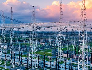 Electrical power substation with transmission towers at sunset.