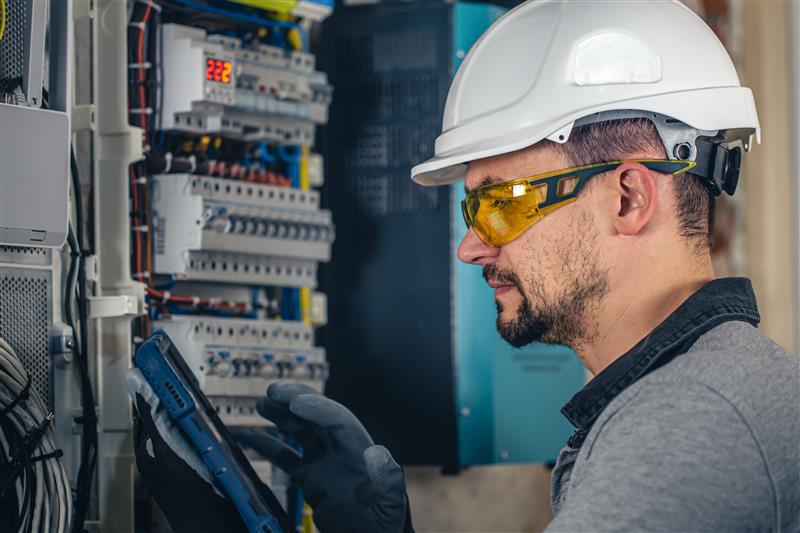 Electrician working on an electrical panel with safety gear.