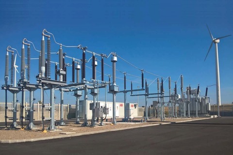 An electrical substation with transformers and power lines under a clear blue sky.