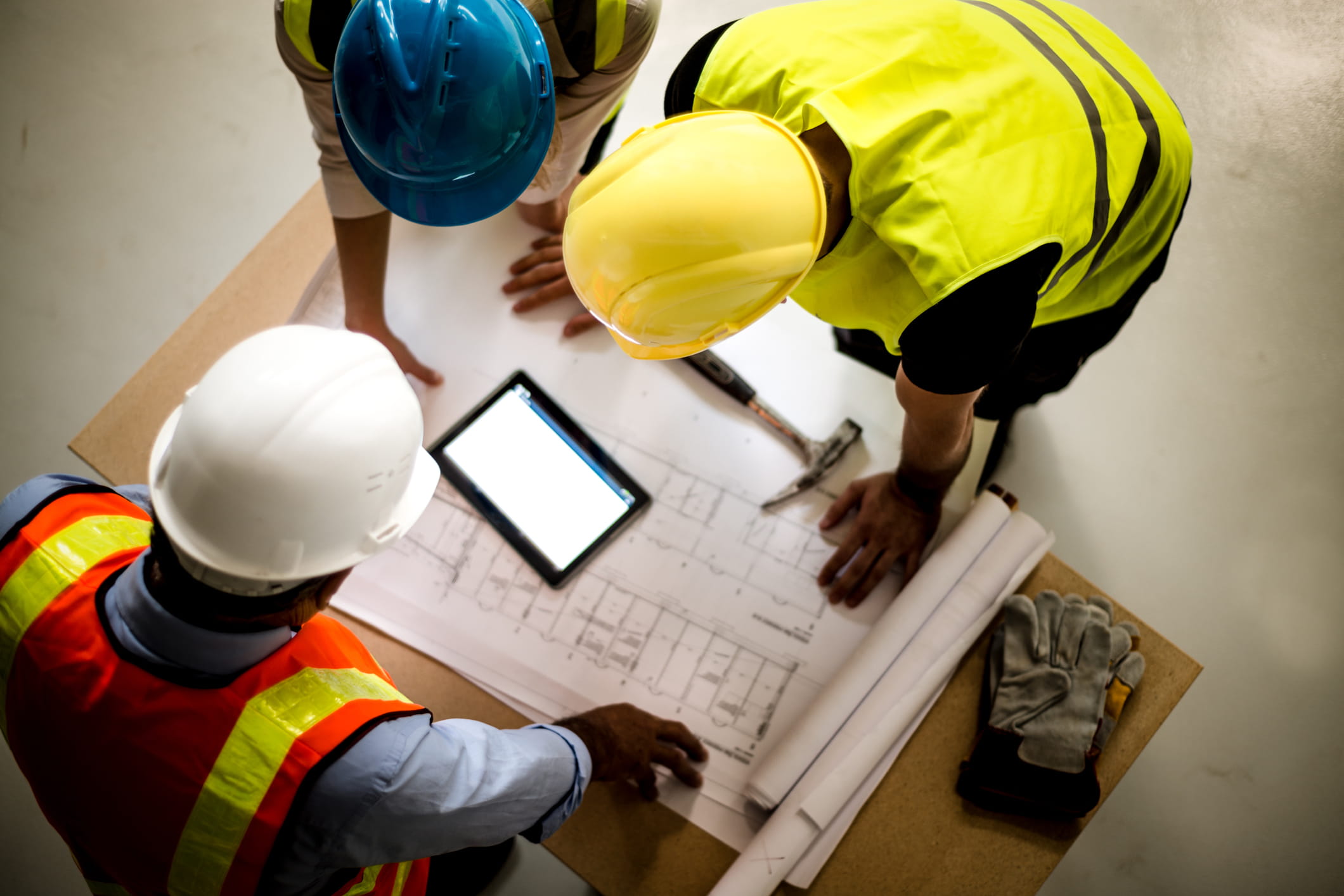 Construction workers reviewing blueprints on site with a tablet.