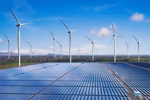 Solar panels with wind turbines under a partly cloudy sky.