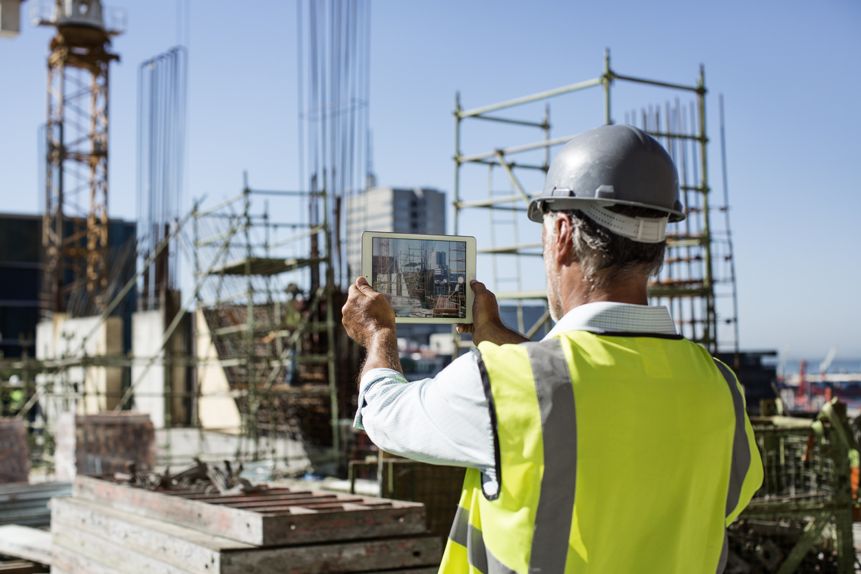 Construction worker using a tablet at a building site.